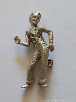 Front view of the silver-toned vaudeville entertainer brooch, showing figure details and two stones on the vest area.
