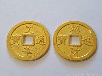 Pair of gold-colored circular metal pendants with square center holes and engraved Chinese characters displayed on white background.