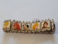 Close-up photo of the silver-tone elastic bracelet showing six princess tiles including Cinderella, Ariel, Snow White, Aurora, and Belle