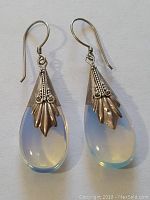 Pair of sterling silver earrings with clear teardrop stones and intricate silver designs, shown from front.