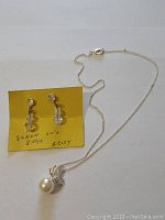 Photo of pearl pendant necklace and aura borealis earrings on card.
