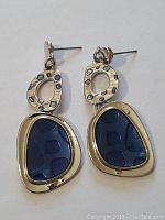 Front view of sterling silver earrings showing blue inlay and abstract open design