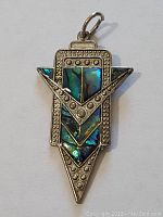 Front view of paua shell pendant showing iridescent shell and textured metal details.