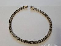 Full view of the braided silver necklace laid flat showing overall length and form.