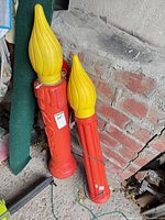 Two red blow mold candles with yellow tops and cords