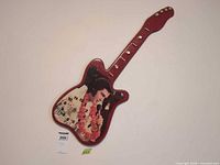 Front view of red guitar-shaped Elvis Presley wall clock on wall