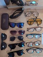 All twelve pairs of eyewear and eyeglass case laid out on table