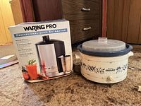 Boxed Waring Pro juice extractor beside Rival Crock-Pot slow cooker