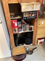 Overall view of shelving unit containing boxed appliances, enamel roasters, baking trays, pans and utensils