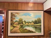 Framed oil painting on wood-panelled wall