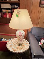 Full view of lamp with shade illuminated on small table