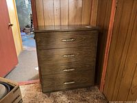 Front view of four-drawer dresser showing laminate finish and metal pulls