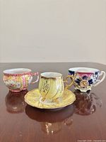 Front view showing three hand-painted cups, yellow cup on saucer