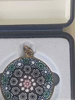 Pendant in box close-up, showing millefiori design and metal bezel