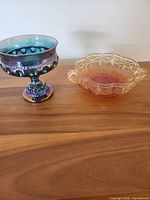 Iridescent pedestal compote and amber dish on wooden surface