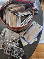 Open round tin filled with stacked loose hockey cards and several sealed Pro Set card packs beside it