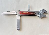 Multi-tool opened showing wrench, serrated blade, file, Phillips driver