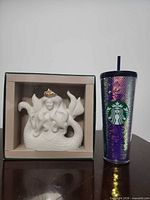 Both items side by side: boxed siren figurine and iridescent tumbler