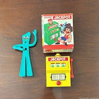 Group shot of slot machine toy, Gumby figure, and box