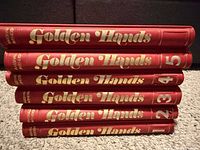 Stack of five red hardcover Golden Hands volumes showing gilt titles and volume numbers on spines