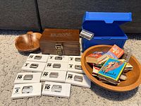 All lot items grouped together showing blade packs, matchbooks, wooden boxes, bowls and blue box
