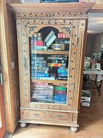 Full view of cabinet showing glass door, inlay, drawers and bun feet