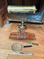 Brass banker lamp, wood organizer, magnifier, pocket knife, brass ruler displayed together