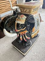 Side view of glazed ceramic elephant garden stool showing multicolor details and rectangular base