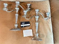 Two matching Gorham sterling silver three-arm candelabra on sofa