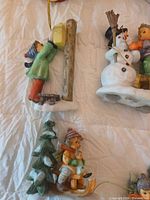 Three Hummel ornaments: child at mailbox, snowman with children, child on sled