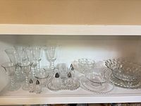 Shelf view showing full assortment: Candlewick stemware, shakers, bowls, plates, Fostoria pieces