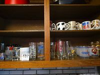 Shelf with mugs, shot glasses and tumblers showing variety