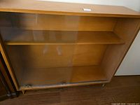 Front view of cabinet showing sliding glass doors and interior shelf