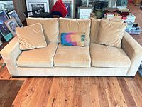 Front view of beige 3-seat sofa with cushions