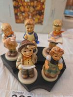 Five M.I. Hummel Club porcelain figurines and display base grouped for overview