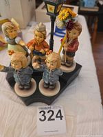 Overall view of five Hummel figurines on display base with street lamp