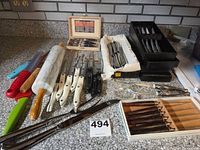 Full lot showing rolling pin, multiple boxed steak knife sets, coloured paring knives, riveted-handle knives and carving utensil