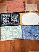 Full grouping of assorted placemats, napkins and quilted protector on floor