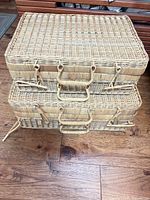 Two stacked wicker rattan suitcases front view showing handles and latches