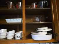 All items on cabinet shelves: snowflake casserole, measuring cups, pie dish, ramekins, oval dishes, lids