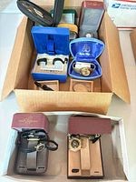 Overview of cardboard box containing four boxed wristwatches and loose bands
