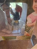 Child with red cap beside tree boxed ornament