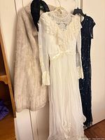 Group shot of wedding dress, evening gown and fur cape hanging on closet door