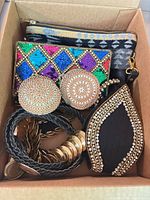 Box view showing sequin clutch, two round beaded coin purses, coin medallion belt, teardrop wristlet
