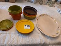 Overview of stacked Tupperware bowls, lids, and Franciscan platter