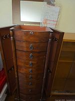 Front view of tall walnut jewelry armoire with lid open and side doors swung out