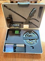 Open hard case showing Spectrum XLT control box, shaft, search coil, cable, battery pack and manuals in foam insert
