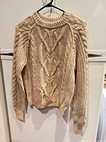 Front view of beige cable knit sweater on hanger