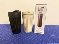 Front view of two ribbed travel mugs and original box