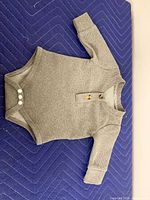 Front view of gray waffle knit bodysuit showing snaps and buttons